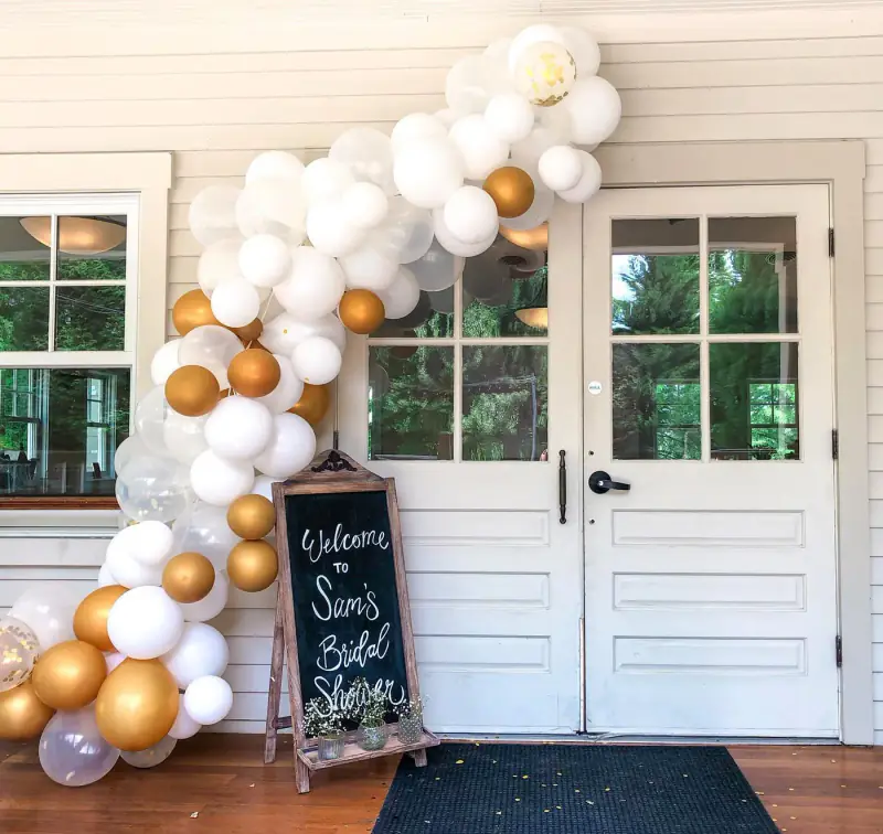 White and gold balloon arch at the door
