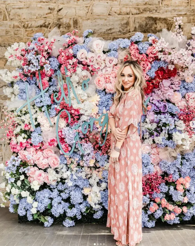Ashley Henson, event stylist and interior designer, in front of a floral wall